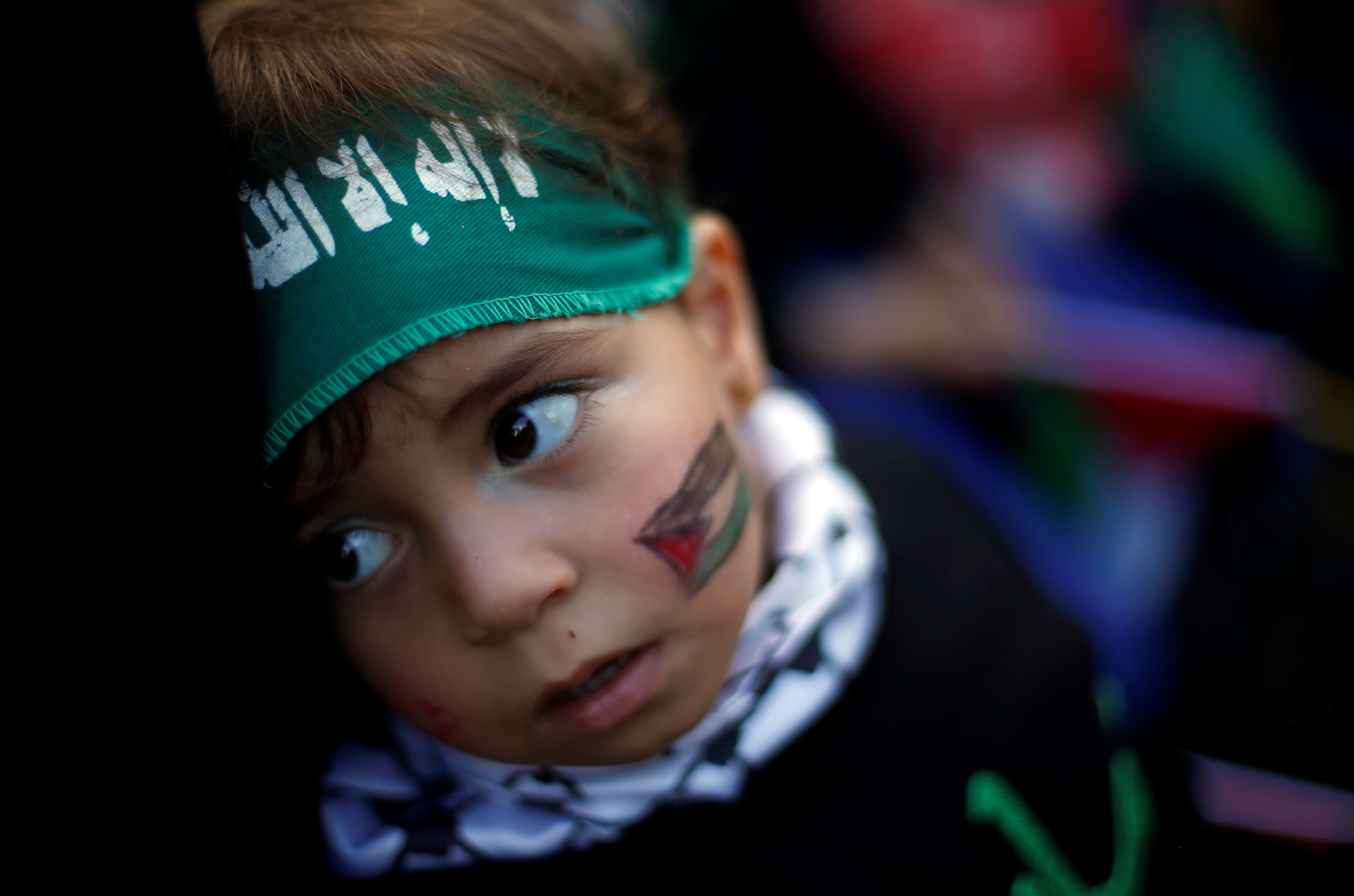 طفل فلسطينى يرسم علم بلده على وجهه