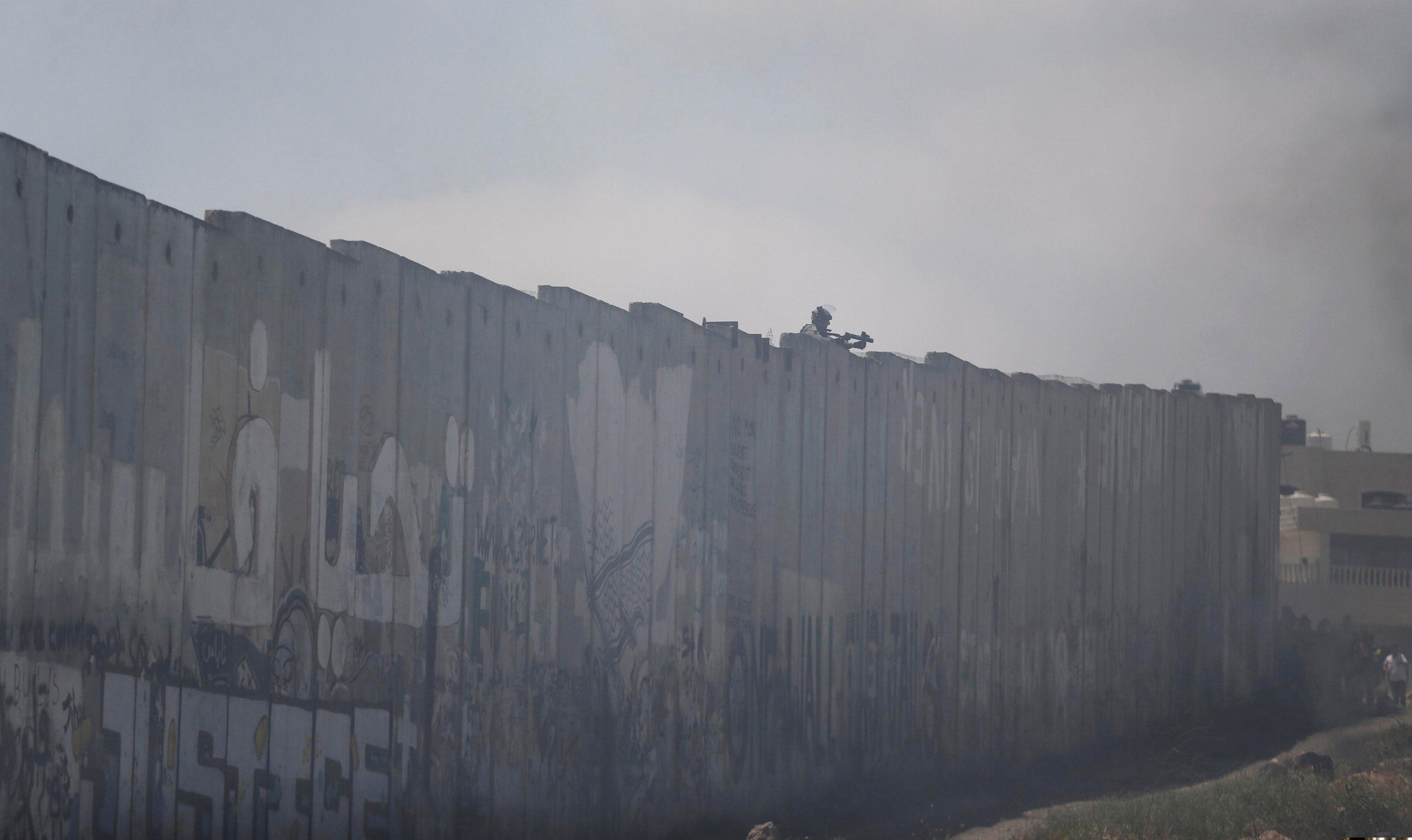 جندى اسرائيلى يصوب سلاحه قرب المتظاهرين الفلسطينين