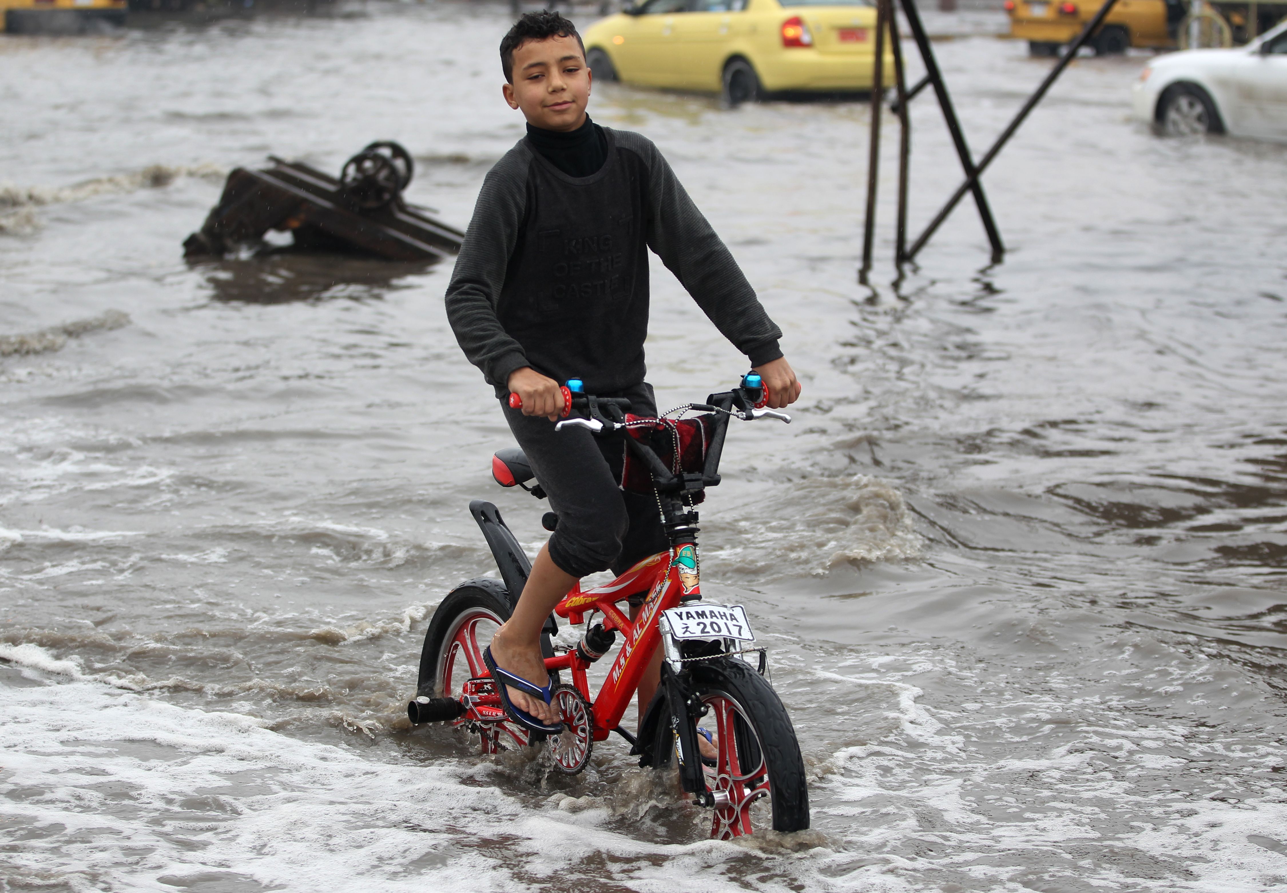 One of the children is playing with his bicycle in the middle of the water