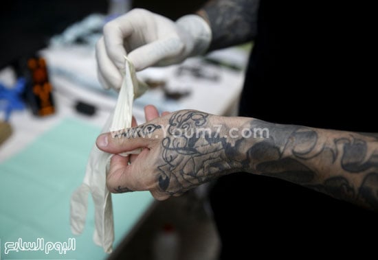 رسام الوشم يرتدى قفازات بلاستيكية قبل بدء الرسم  -اليوم السابع -10 -2015