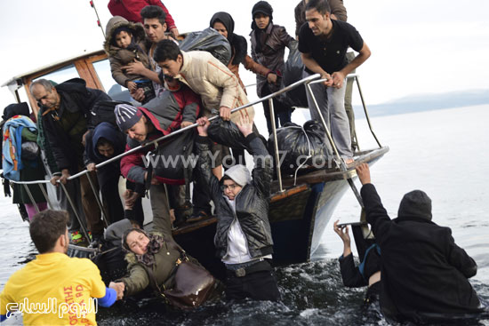 بعض عمال الإنقاذ يساعدون اللاجئين الجدد الوافدين -اليوم السابع -11 -2015
