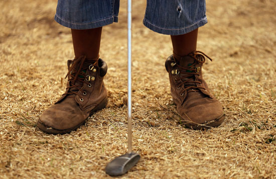 طفل يبلغ من العمر 10 سنوات يستعد لرمى كرة الجولف خلال مسابقة جولف محلية فى حديقة Katlehong – جوهانسبرج – جنوب أفريقيا  -اليوم السابع -12 -2015