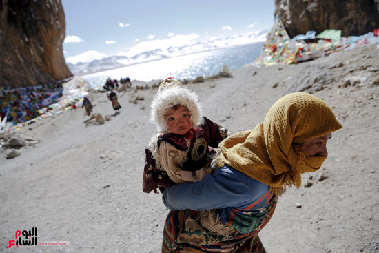 امرأة من قبيلة التبت تحمل طفلها أثناء زيارتها إلى بحيرة ناميتسو بمنطقة التبت -اليوم السابع -12 -2015