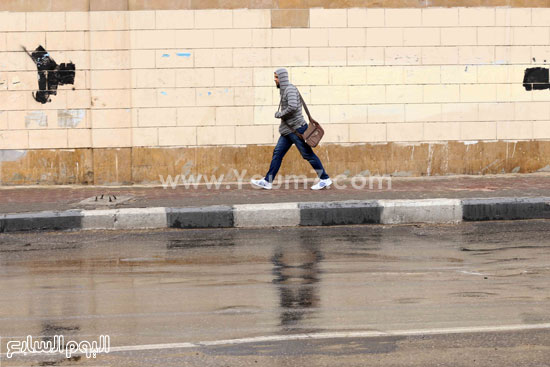  شخص يحتمى من المطر بأحد الأسوار -اليوم السابع -4 -2015