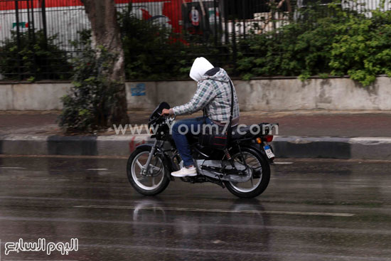  شخص يغطى رأسه لتفادى الأمطار الشديدة  -اليوم السابع -4 -2015