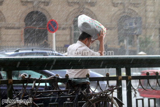  شاب يضع حقيبة بلاستيكية على رأسه لتحميه من المطر  -اليوم السابع -4 -2015