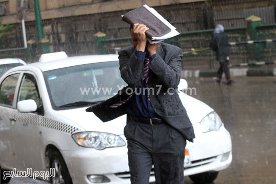  رجل يحتمى من المطر بوضع الأوراق على رأسه  -اليوم السابع -4 -2015