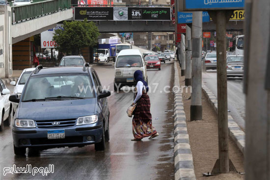  فتاة تحاول عبور الطريق وسط تساقط الأمطار  -اليوم السابع -4 -2015