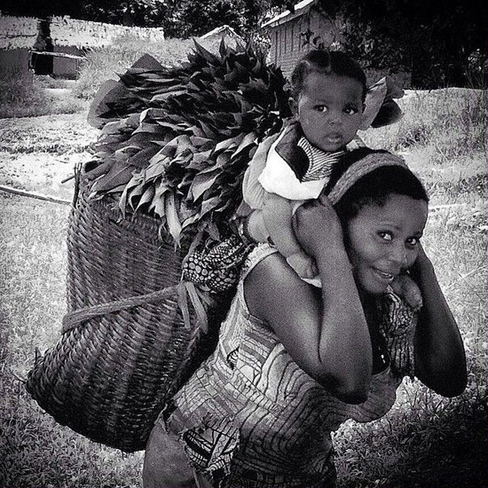 أم تحمل طفلها مع سلة من النباتات التى جمعتها من الحقل  -اليوم السابع -4 -2015