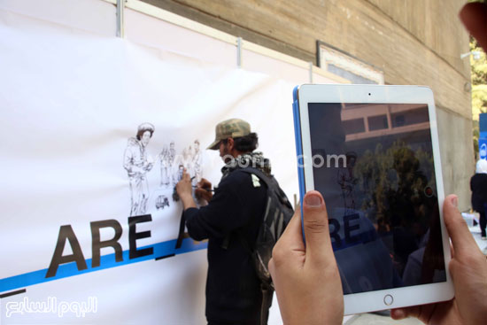 أحد المارة يلتقط صورًا لمحمد وهو يرسم. -اليوم السابع -4 -2015