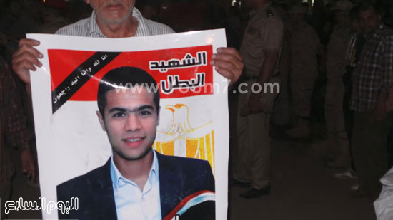 	أحد الاهالى المشاركون بالجنازة يرفع صورة الشهيد أحمد عبدالسلام -اليوم السابع -4 -2015