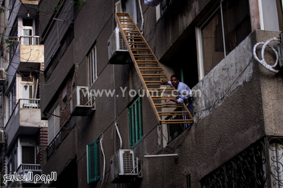 أحد الأهالى يحاول الصعود على سلم للوصول إلى الشقة المنكوبة -اليوم السابع -4 -2015