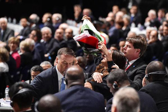 متظاهرة ترفع علم فلسطين تأييدا لها داخل قاعة اجتماع الجمعية العمومية للفيفا، والأمن يقوم بإخراجها من القاعة -اليوم السابع -5 -2015