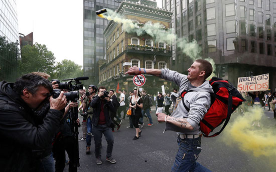 	متظاهر يرمى قنبلة غاز أثناء مظاهرة مناهضة للتقشف فى لندن  -اليوم السابع -5 -2015