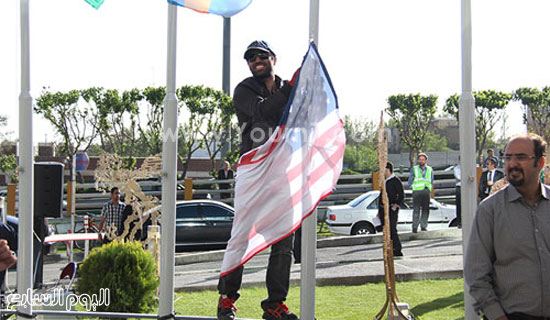  	إيرانى يرفع العلم الأمريكى فى إيران وهو مبتسما -اليوم السابع -5 -2015