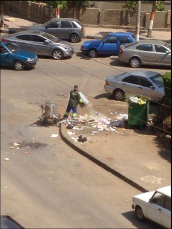 صورة توضح إلقاء العامل القمامة على الرصيف -اليوم السابع -6 -2015