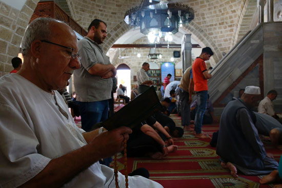 فلسطيني يجلس يقرأ القرآن في مسجد سيد هاشم في مدينة غزة -اليوم السابع -6 -2016