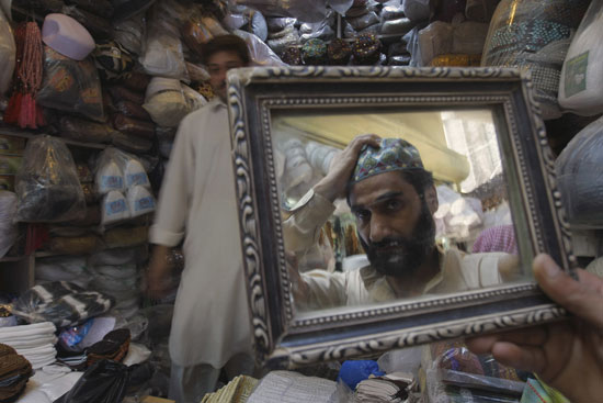 باكستاني يجرب طاقية تقليدية في أحد الأسواق بباسكتان -اليوم السابع -6 -2016