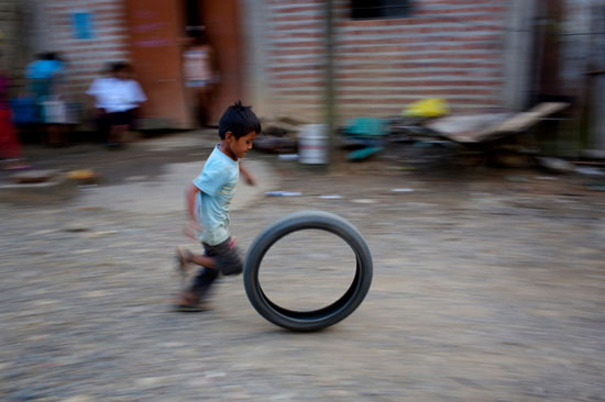 طفل صغير يلعب بإطار دراجة نارية فارغ فى بيرو  -اليوم السابع -7 -2015