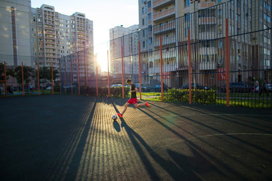 شاب روشى يلعب كرة القدم فى حين يتعلم البرازيليين لعب كرة القدم فى الشوارع أو الشواطئ تكون الملاعب فى روسيا بين المنازل إسفلتية وتكون تمهيدا للاعبين للانضمام للمنتخب الروسى -اليوم السابع -7 -2015