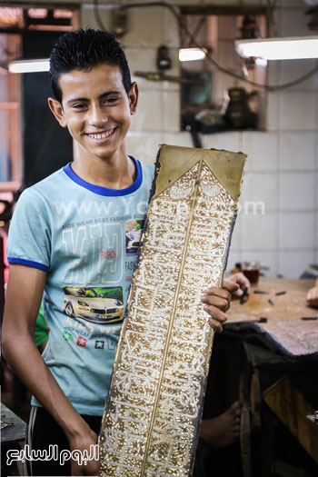 أحد صغار العاملين يحمل قطعة فنية من النحاس -اليوم السابع -8 -2015