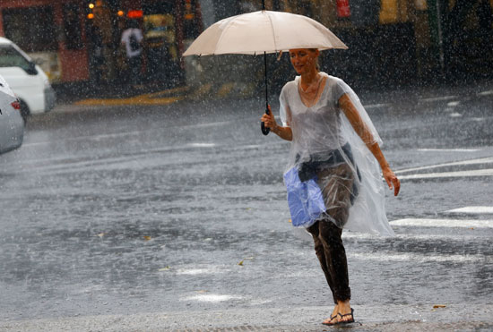  امرأة تحمل مظلة وتحاول عبور الشارع وسط الأمطار الغزيرة للغاية فى منطقة جينزا بالعاصمة اليابانية طوكيو  -اليوم السابع -9 -2015