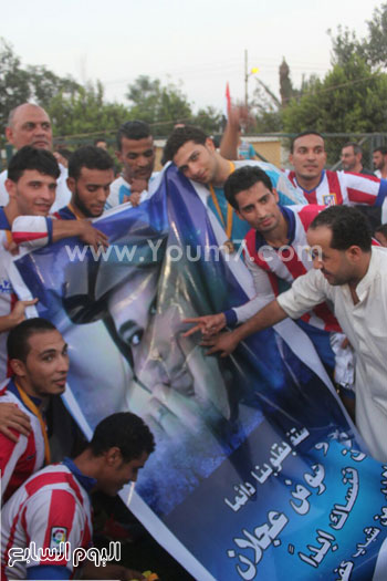 اللاعبون يحملون إحدى اللافتات تحمل صورة شهيد بالقرية -اليوم السابع -9 -2015