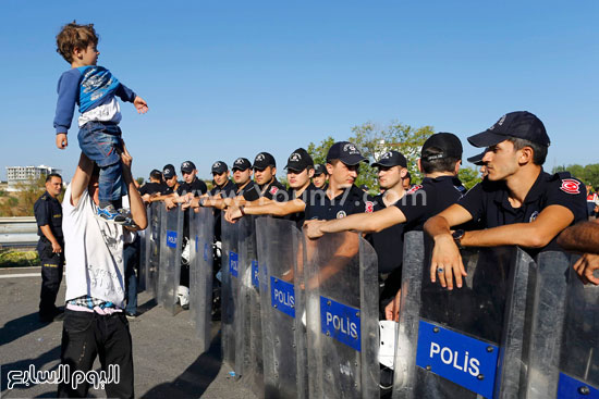 أحد الأشخاص يرفع ابنه عاليا فى محاولة للضغط على قوات الشرطة  -اليوم السابع -9 -2015