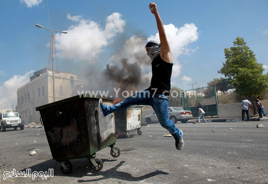 أحد الشباب الفلسطينيين يحرق صندوق قمامة أمام القوات الإسرائيلية -اليوم السابع -9 -2015