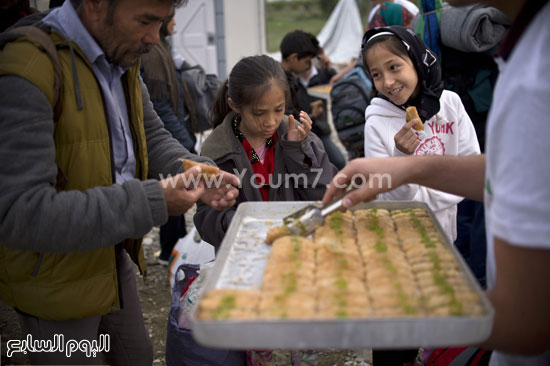 توزيع البقلاوة على المحتفلين بالعيد من اللاجئين على الحدود المقدونية اليونانية. -اليوم السابع -9 -2015