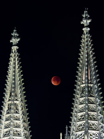  القمر الدامى بين أبراج كاتدرائية كولونيا أثناء خسوف القمر الكلى فى كولونيا بغرب ألمانيا -اليوم السابع -9 -2015