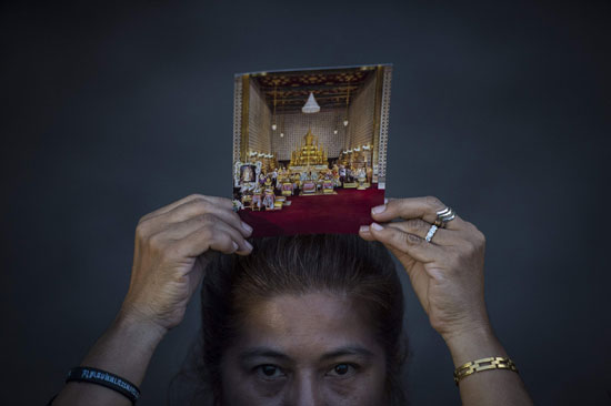 سيدة تضع صورة لملك تايلاند الراحل على رأسها