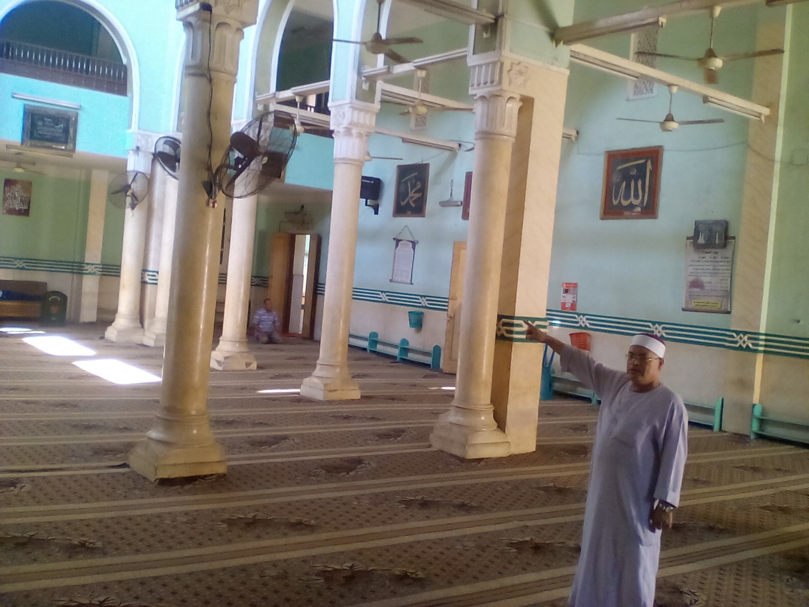امام المسجد  يشير الي القطع الاثري في المسجد
