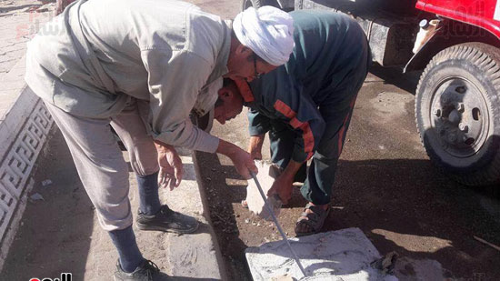 عمال النظافة يضعون أغطية أسمنتية على البالوعات