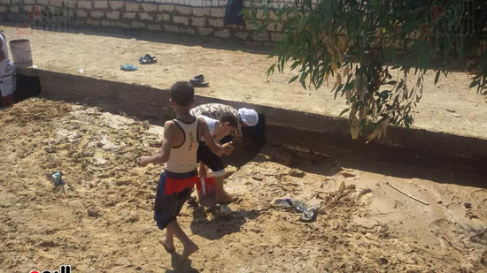 طفلين يساعدا والدهم فى رفع المياه عن المقابر