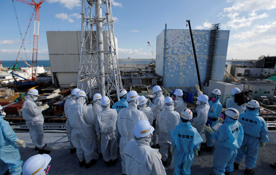 عدد من موظفى هيئة الطاقة النووية فى اليابان يتجمعون حول محطة فوكوشيما 