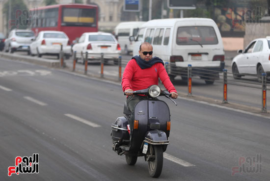 شخص يقود دراجة نارية مرتديا زيا ثقيلا بسبب برودة الجو