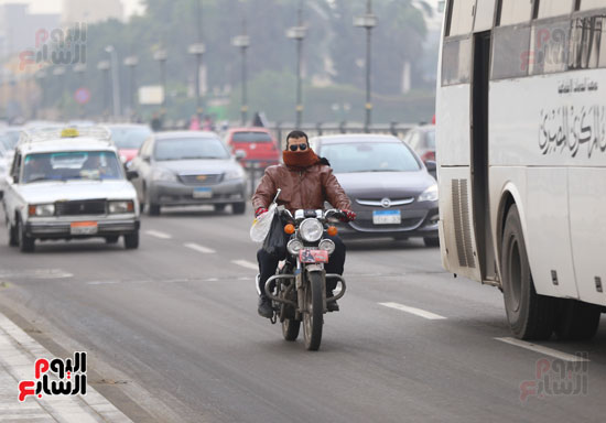 شخص آخر يقود دراجة نارية مرتديا ملابس ثقيلة بسبب موجة الطقس السيئ