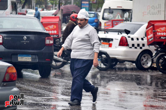 مواطن يغطى رأسه بكيس بلاستيكى خشية الأمطار
