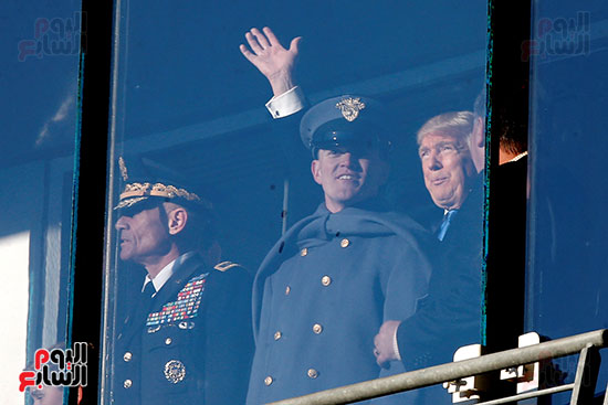 الرئيس المنتخب دونالد ترامب يلوح لحشد وهو يقف مع أفراد الجيش الأمريكي خلال مبارة كرة قدم لأفراد البحرية الأمريكية