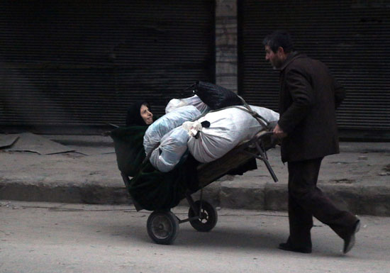مواطن يحمل سيدة سورية على عربة شرق حلب