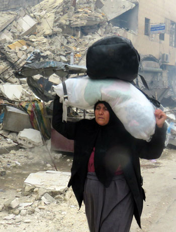 نازحة سورية تحمل أمتعتها شرق مدينة حلب