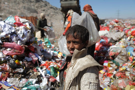 طفل يمنى يقف وسط جبل القمامة 