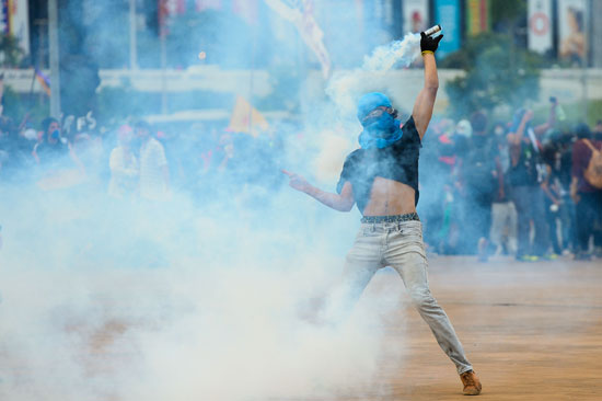 متظاهر يحمل قنبلة غاز