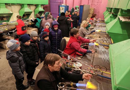  أطفال أوكرانيون يشاهدون عاملة تصنع الزجاج اللازم لتزين هدايا عيد الميلاد "الكريسماس" .