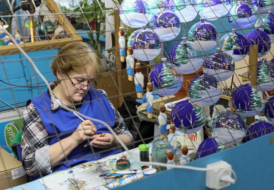  عاملة ترسم على الزجاج فى أحد المصانع لصنع هدايا الكريسماس فى قرية كلاديفيدوف بأوكرانيا