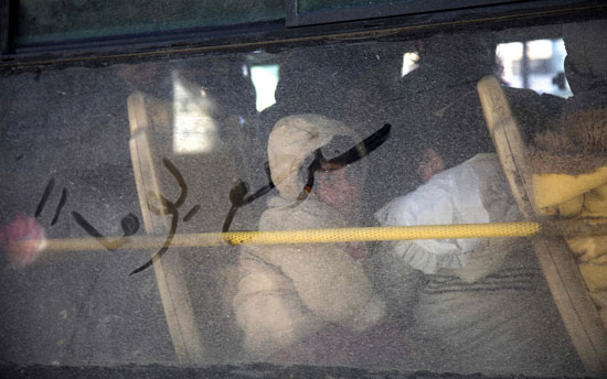 أطفال سوريون يستقلون حافلة خارجة من حلب السورية