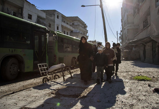 سيدة سورية تأخذ أطفال لتستقل سيارة للخروج من حلب السورية