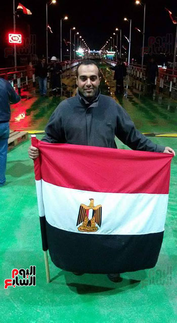 احد عمال الترسانة البحرية يرفع علم مصر علي الكوبري عقب انتهاء اعماله
