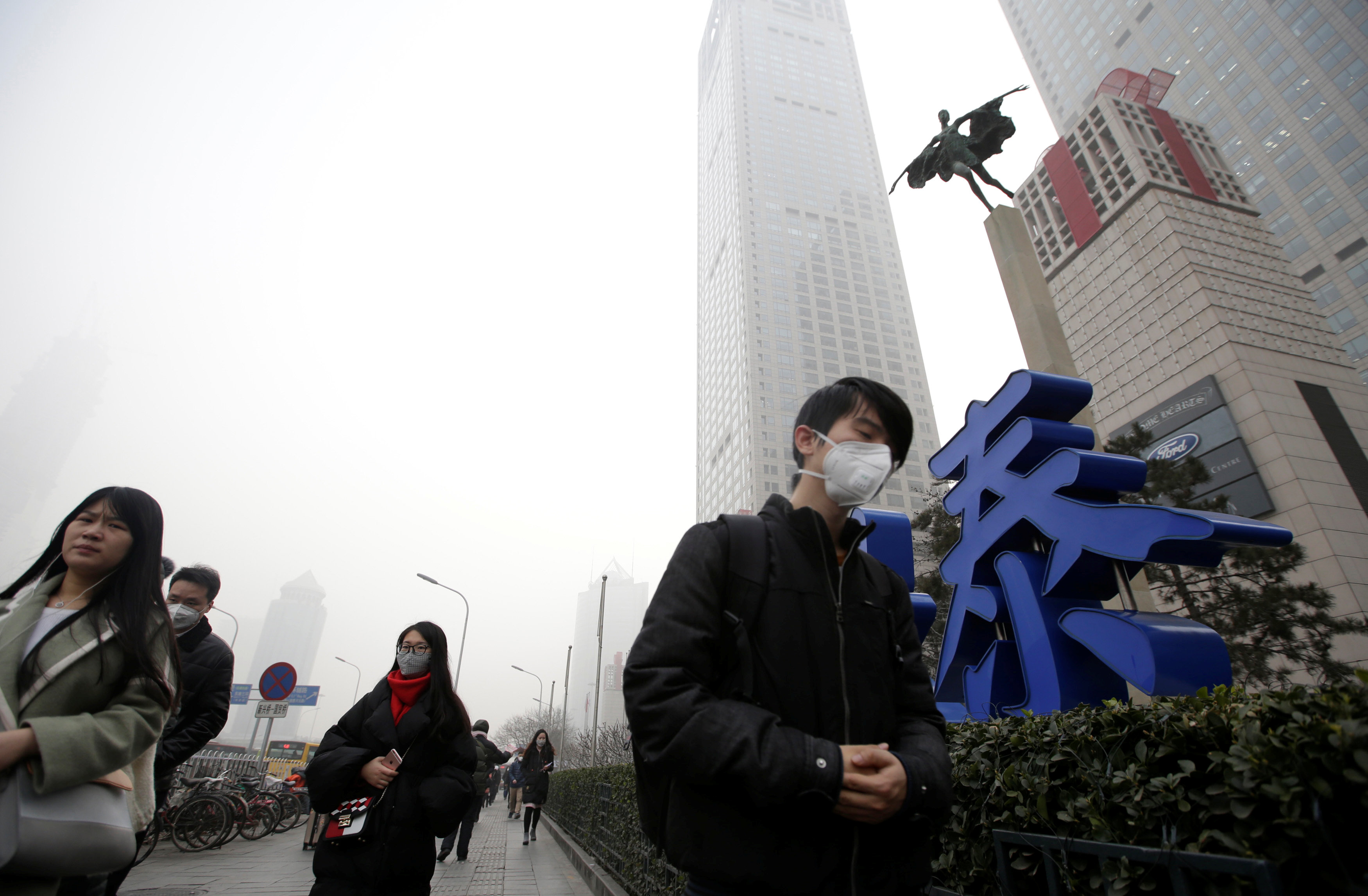 صينيون يرتدون كمامات للحماية من التلوث الجوى اثناء ذاثناء سيرهم بالقرب من احد المراكز في بكين - رويترز